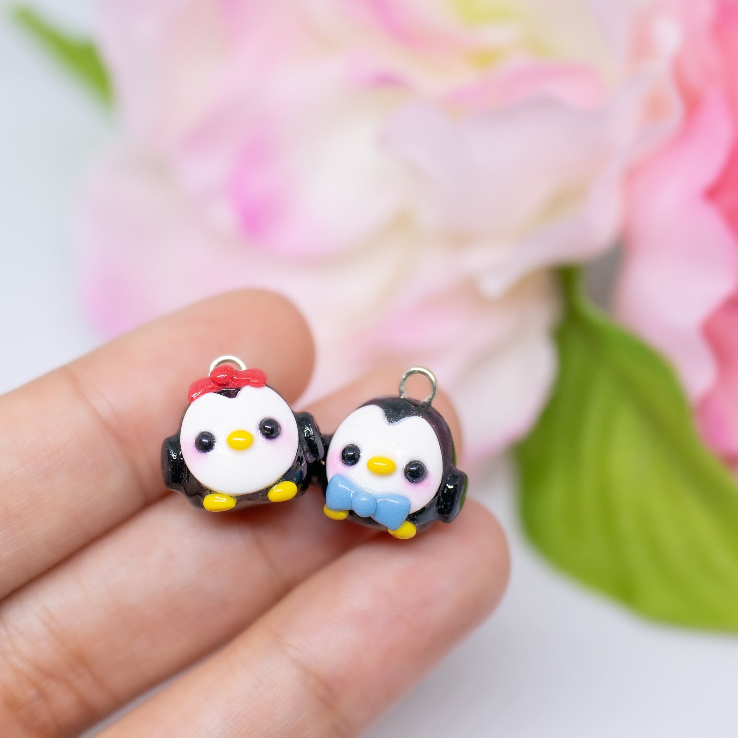 Handmade polymer clay penguin charms. They come as a pair, one with a red bow and one with a blue bow.