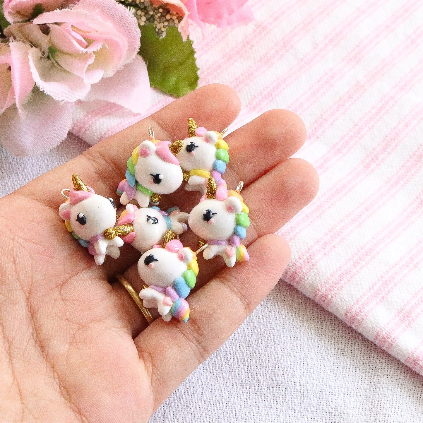 A chubby, rainbow unicorn with a gold bell and unicorn horn. They can be used as phone charms, earrings or planner charms!