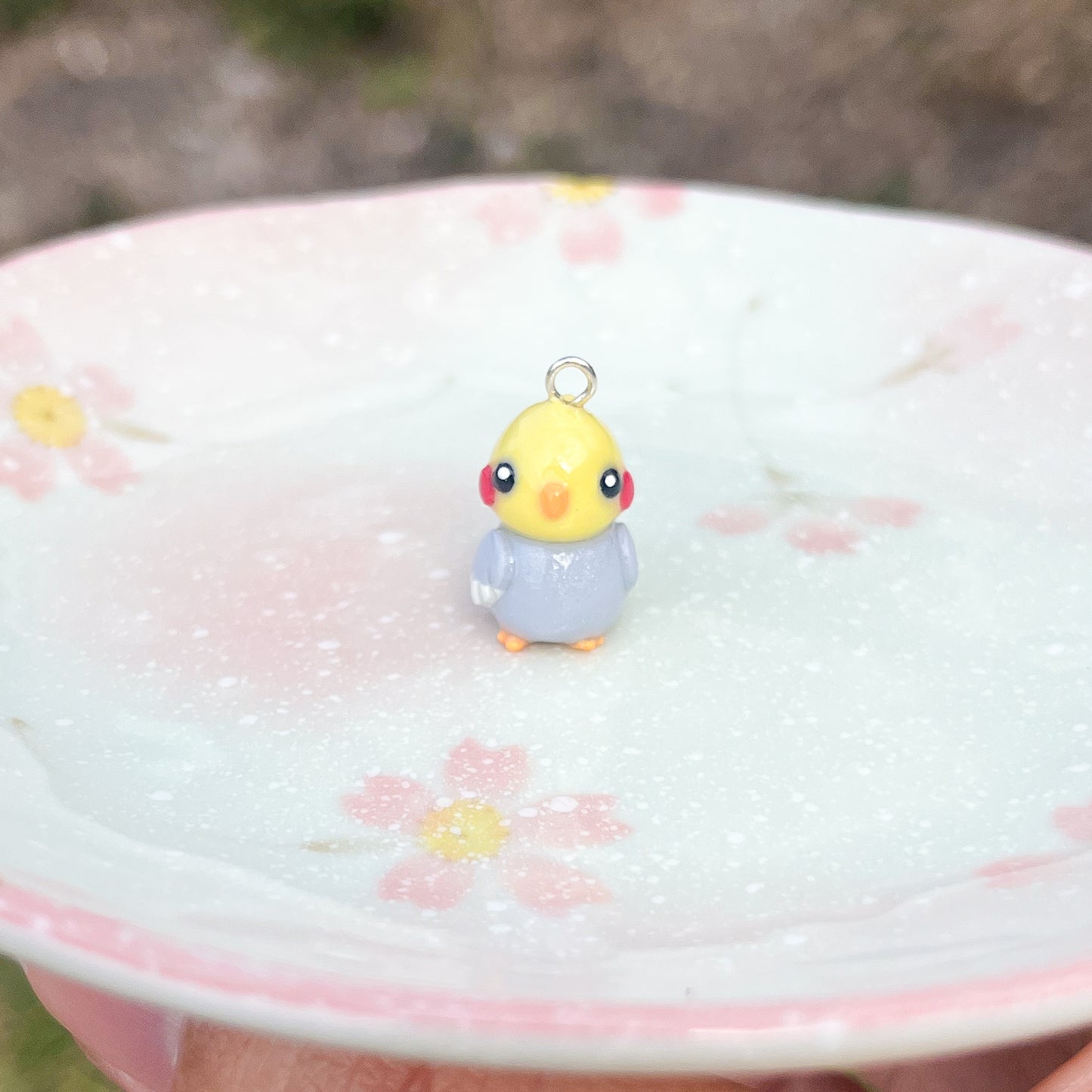 Handmade polymer clay cockatiel charms. This little bird has an orange beak/feet, and cute rosy-red cheeks.
