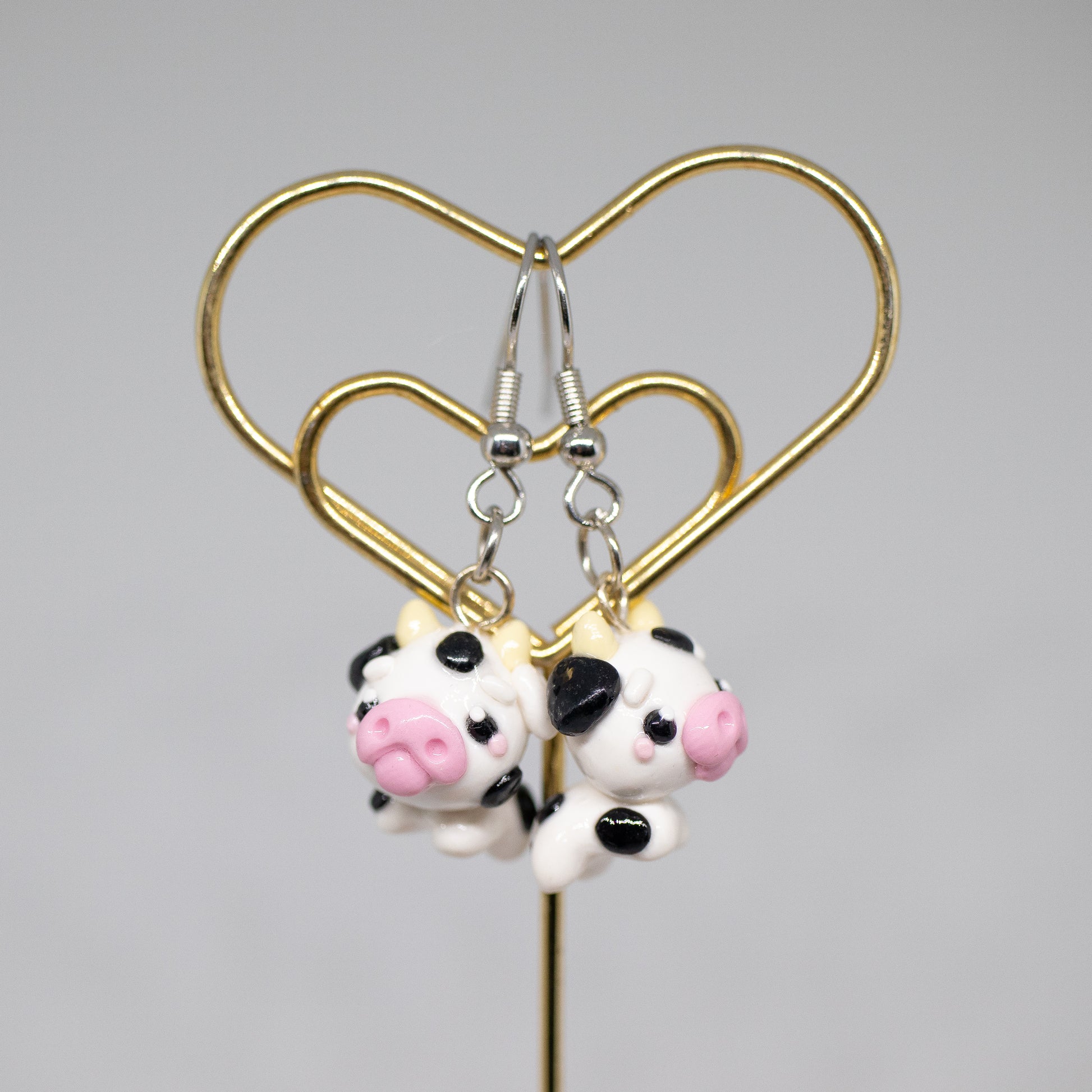 Handmade polymer clay cow charm.  This cow has black spots and a cute pink snout. Available as a phone charm or pair of earrings. Makes as a great little gift to a friend that loves cows.