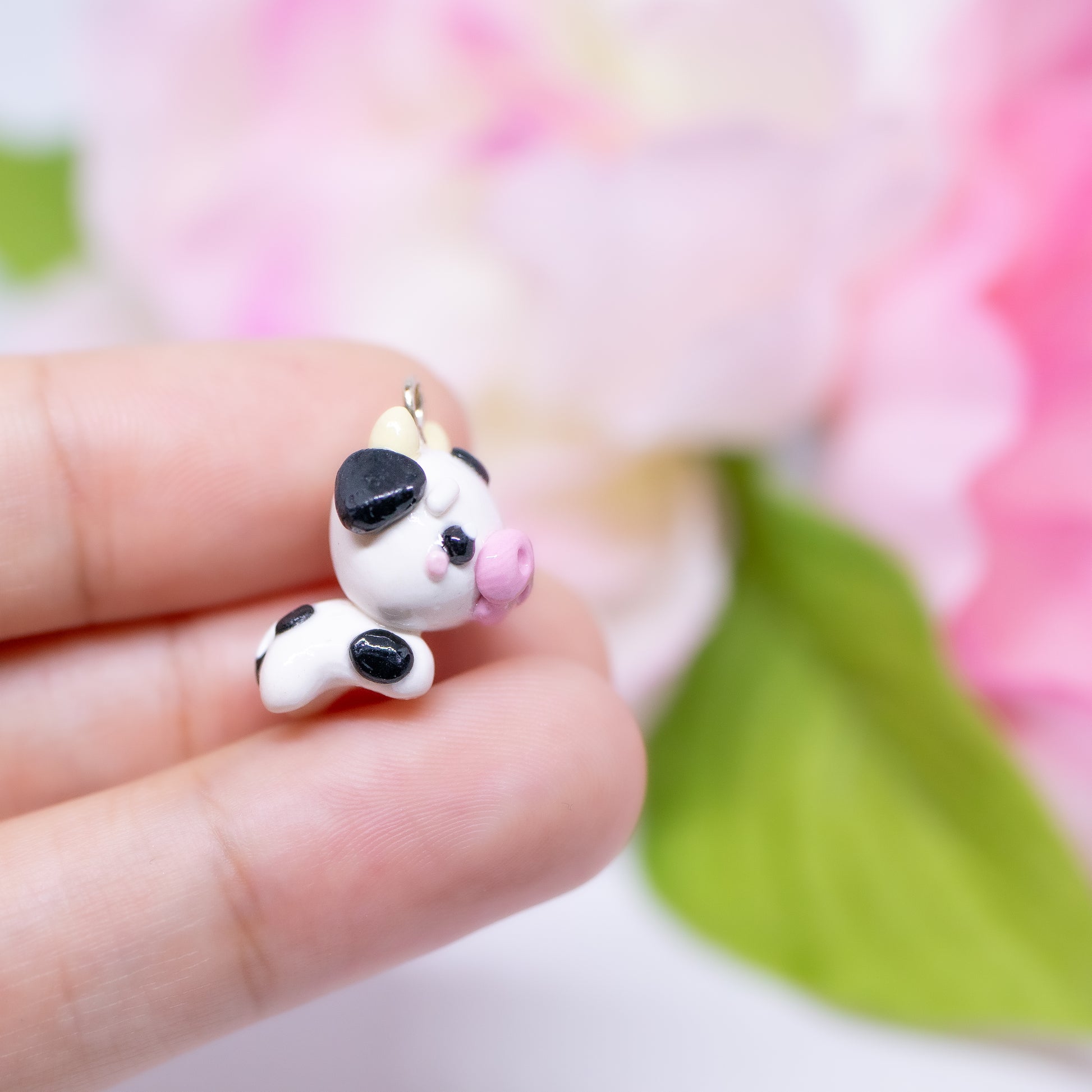 Handmade polymer clay cow charm.  This cow has black spots and a cute pink snout. Available as a phone charm or pair of earrings. Makes as a great little gift to a friend that loves cows.