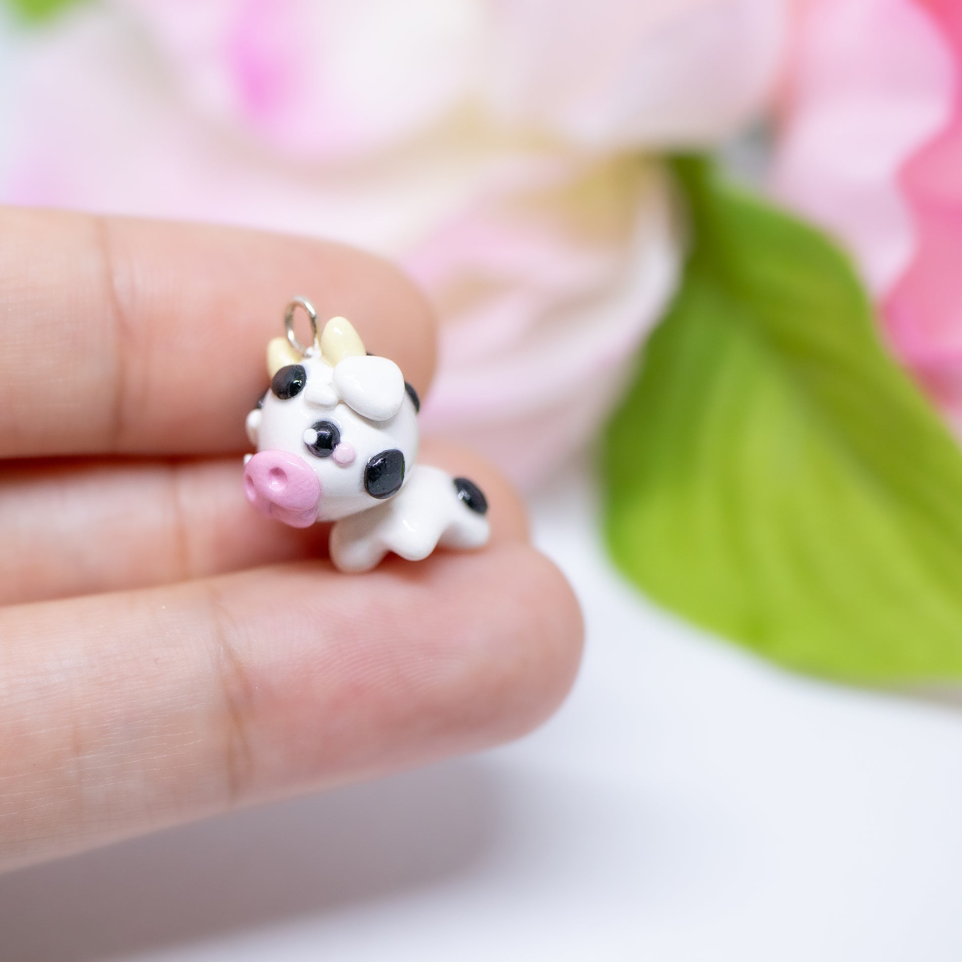 Handmade polymer clay cow charm.  This cow has black spots and a cute pink snout. Available as a phone charm or pair of earrings. Makes as a great little gift to a friend that loves cows.