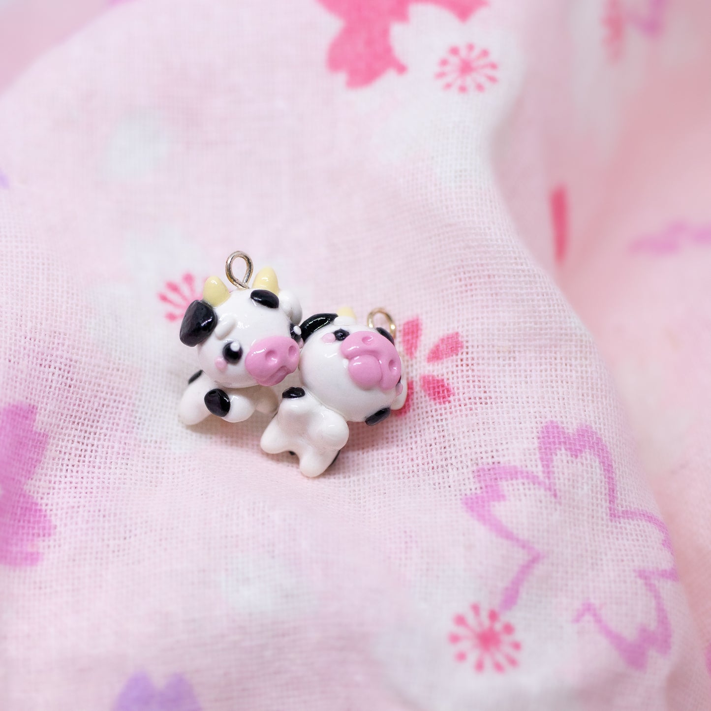 Handmade polymer clay cow charm.  This cow has black spots and a cute pink snout. Available as a phone charm or pair of earrings. Makes as a great little gift to a friend that loves cows.