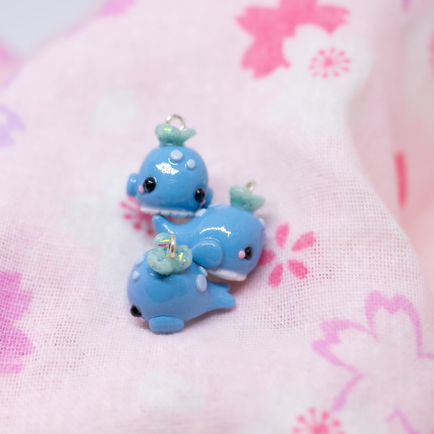 Handmade polymer clay blue whale charms. Available as a pair of earrings or as a charm. This little blue whale has spots on it's forehead and a glittery water splash coming out of its head.