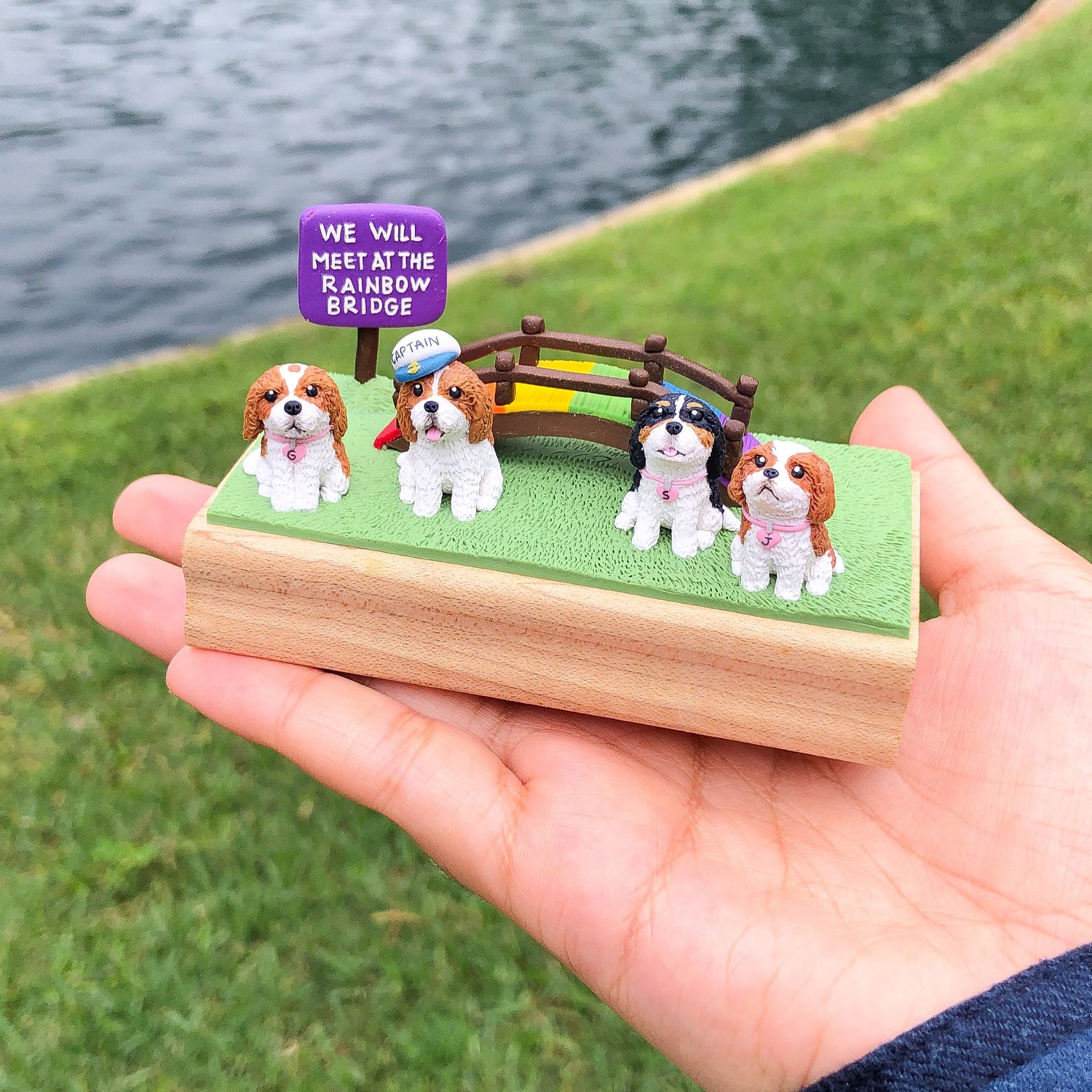 A custom polymer clay and wood figurine of a rainbow bridge and four doggies.