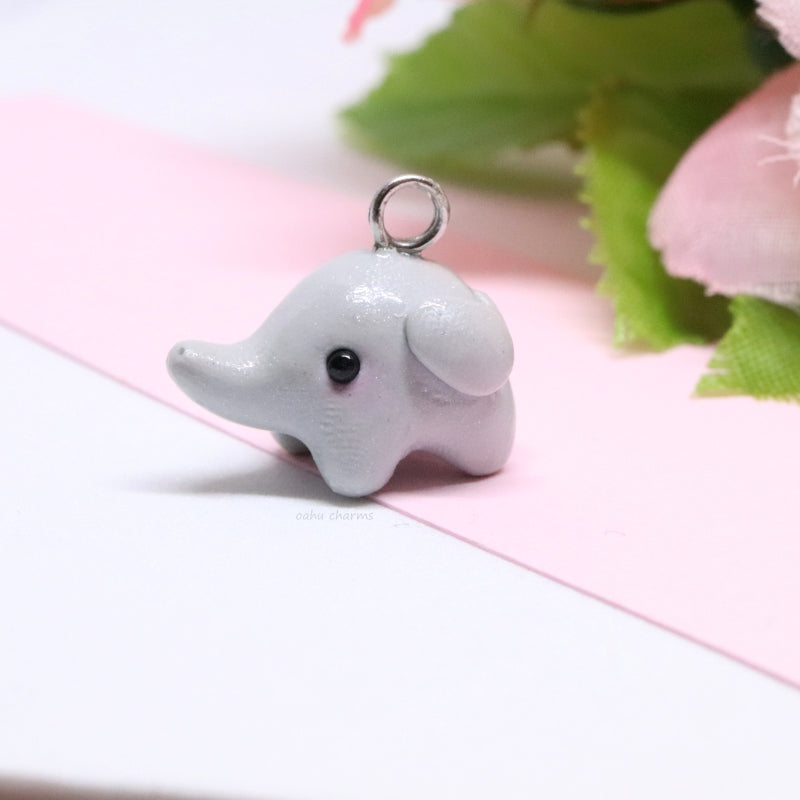 A simple, grey elephant charm. This charm is sculpted mainly from one ball of clay. There's lots of tiny details like ears and a curly tail. Size: 0.5” wide x 0.625” tall.