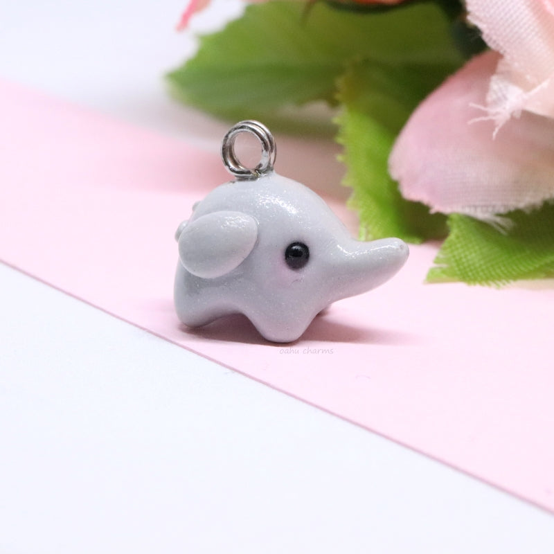 A simple, grey elephant charm. This charm is sculpted mainly from one ball of clay. There's lots of tiny details like ears and a curly tail. Size: 0.5” wide x 0.625” tall.