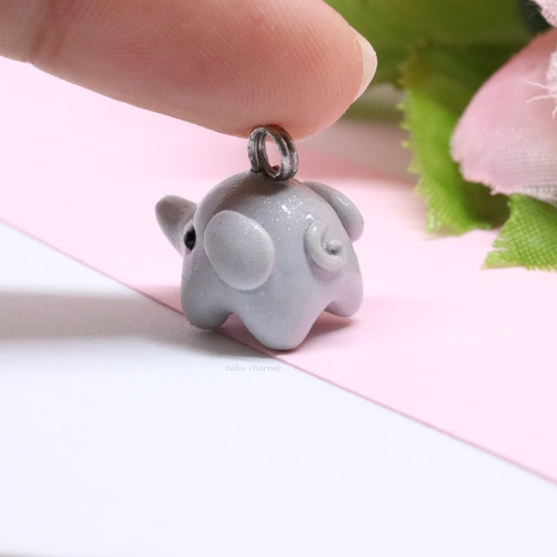 A simple, grey elephant charm. This charm is sculpted mainly from one ball of clay. There's lots of tiny details like ears and a curly tail. Size: 0.5” wide x 0.625” tall.