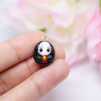 Handmade polymer clay no face charm inspired by the movie spirited away. The no face is holding a little red bath token in it's hands.