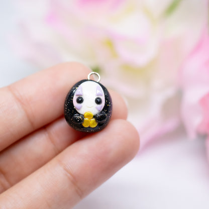 Handmade polymer clay no face charm inspired by the movie spirited away. The no face is holding little gold coins in it's hands.