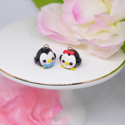 Handmade polymer clay penguin charms. They come as a pair, one with a red bow and one with a blue bow.