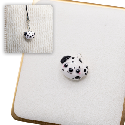 A picture of a dalmation polymer clay dog charm on a white display with a gold border. There is a 2nd smaller photo of the same dog charm being hung with a phone strap against a textured background.