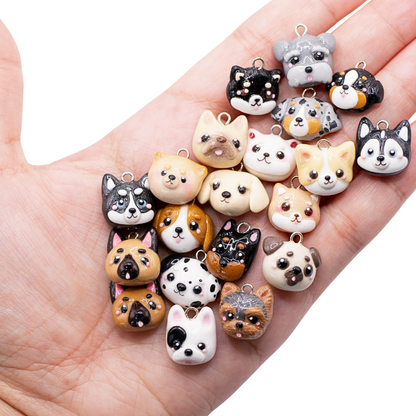 A hand holding a collection of 20 different handmade clay dog charms on a white background.