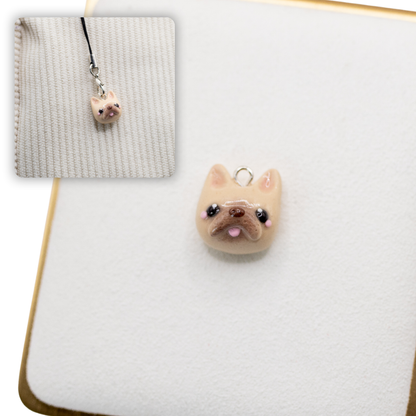A picture of a french bulldog polymer clay dog charm against a white background, with a 2nd smaller photo of the same dog charm being hung with a phone strap against a textured background.