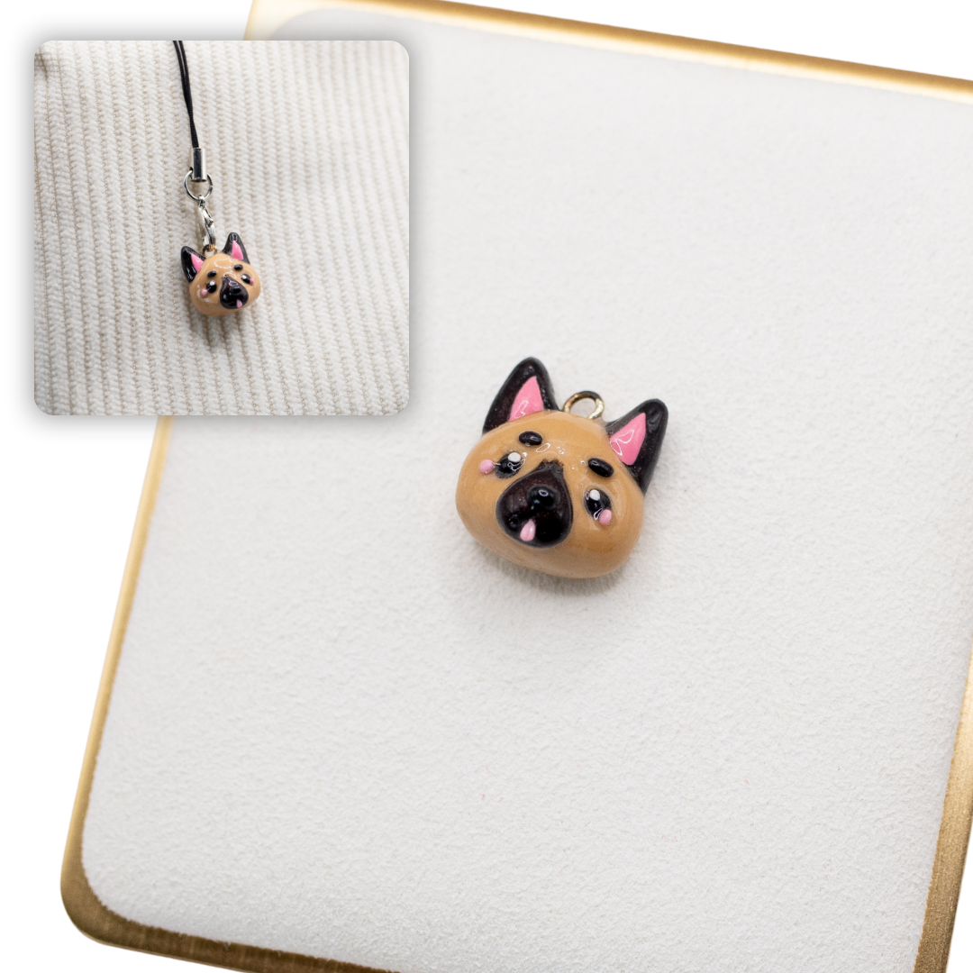 A picture of a german shepherd dog polymer clay dog charm on a white display with a gold border. There is a 2nd smaller photo of the same dog charm being hung with a phone strap against a textured background.