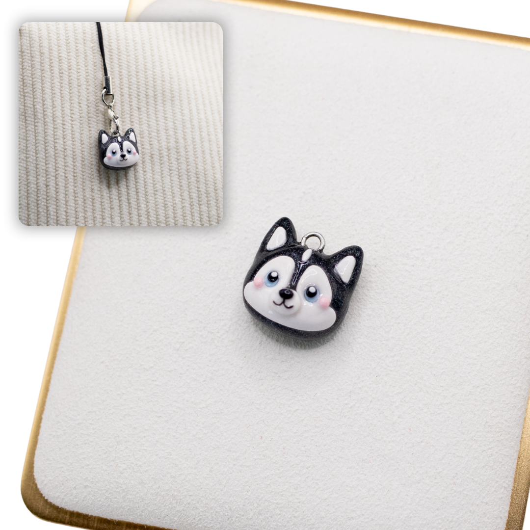 A picture of a husky dog polymer clay dog charm on a white display with a gold border. There is a 2nd smaller photo of the same dog charm being hung with a phone strap against a textured background.