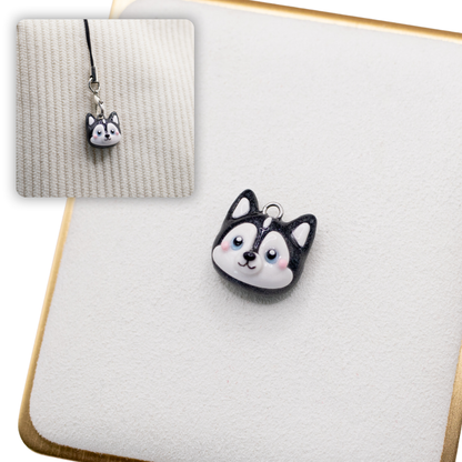 A picture of a husky dog polymer clay dog charm on a white display with a gold border. There is a 2nd smaller photo of the same dog charm being hung with a phone strap against a textured background.