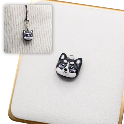 A picture of a husky dog polymer clay dog charm on a white display with a gold border. There is a 2nd smaller photo of the same dog charm being hung with a phone strap against a textured background.