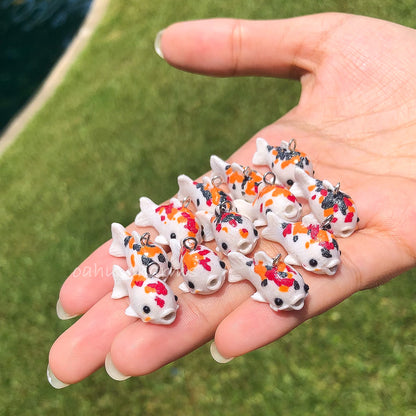 A handful of koi clay charms. These koi charms come in a variation of colors with red, orange, and black spots.