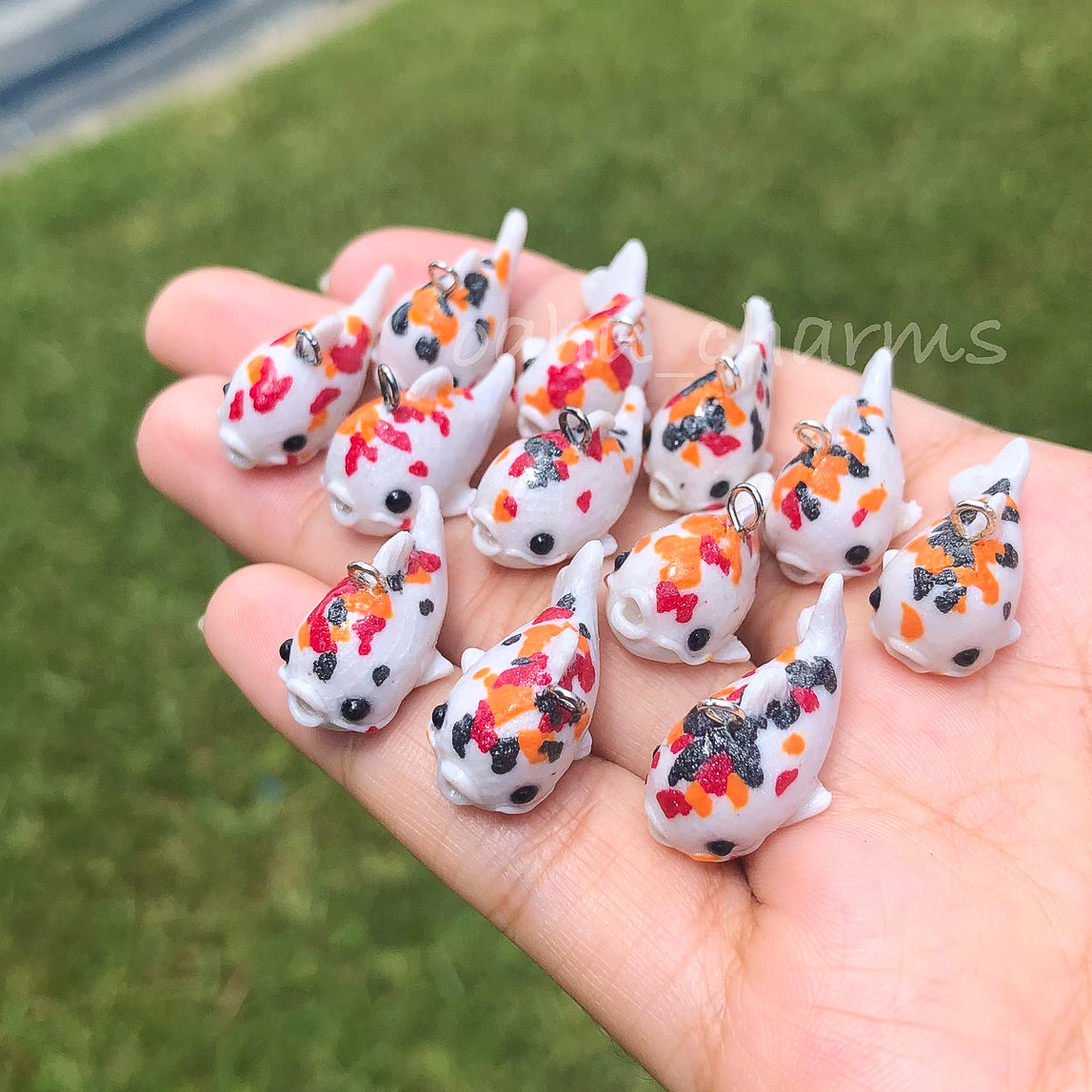 A handful of koi clay charms. These koi charms come in a variation of colors with red, orange, and black spots.