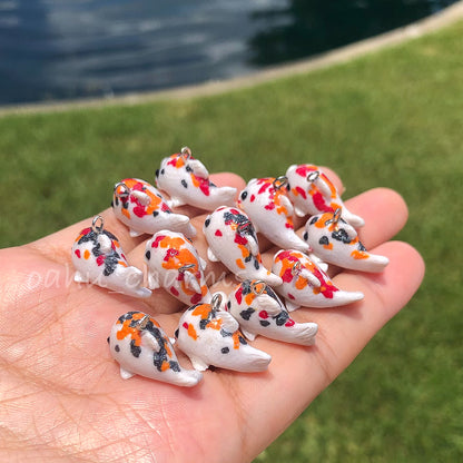 A handful of koi clay charms. These koi charms come in a variation of colors with red, orange, and black spots.