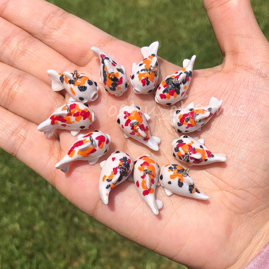 A handful of koi clay charms. These koi charms come in a variation of colors with red, orange, and black spots.