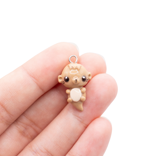 Small otter polymer clay charm held in a hand with a white background.