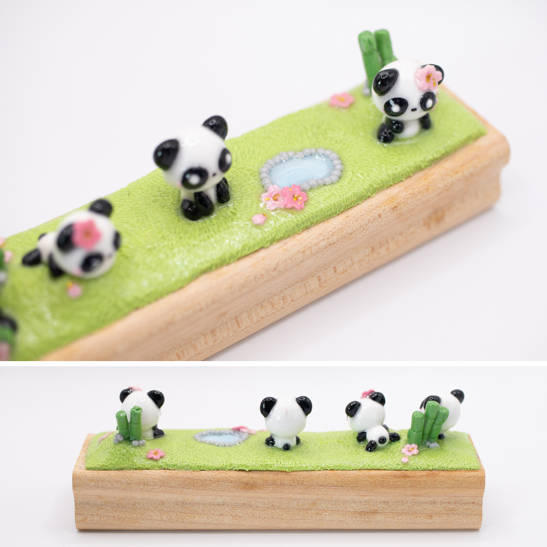 A clay figurine of mini pandas on a wood block.
