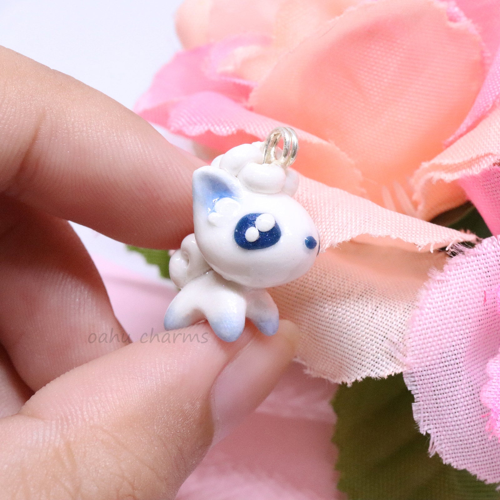 A cute, simple alolan vulpix clay charm.  This charm has a lot of little details on it like large, blue eyes and a big furry tail. Can be attached onto a phone, planner, or keychain.