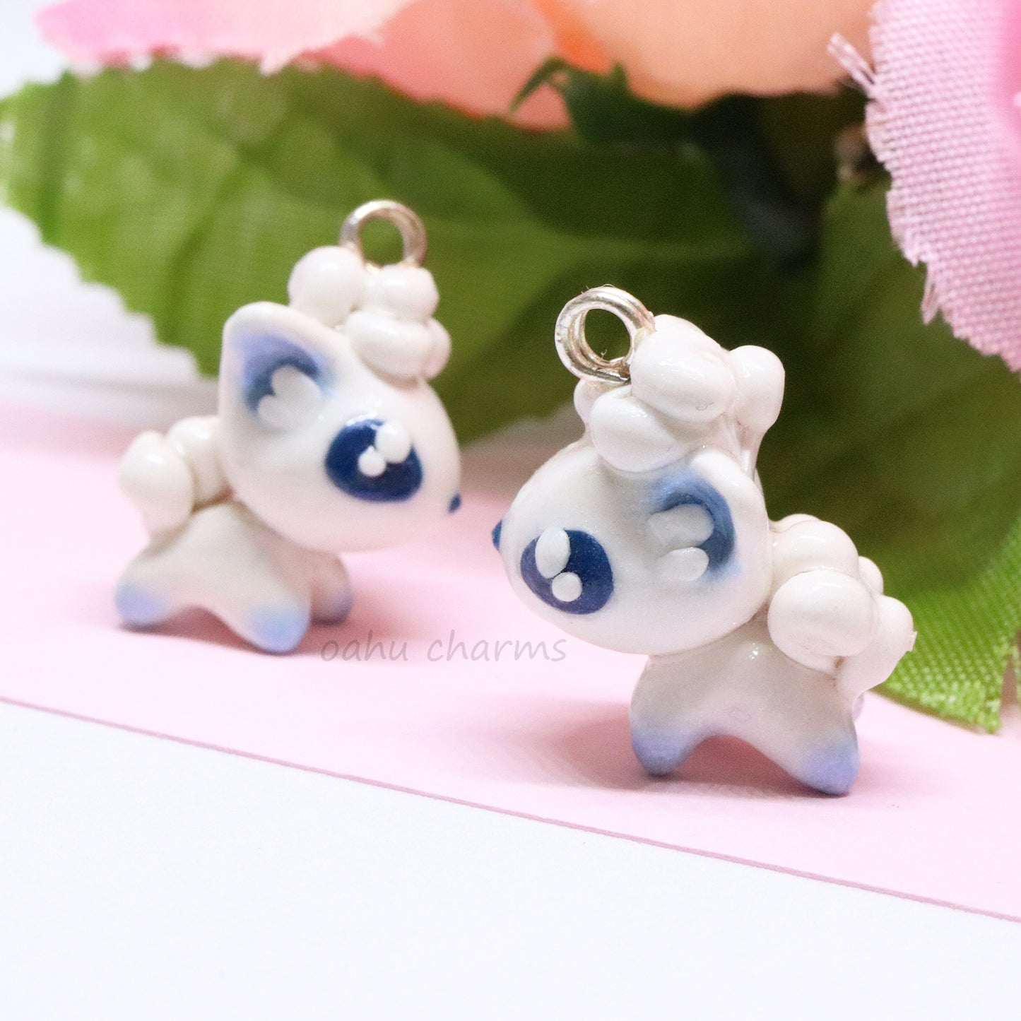 A cute, simple alolan vulpix clay charm.  This charm has a lot of little details on it like large, blue eyes and a big furry tail. Can be attached onto a phone, planner, or keychain.